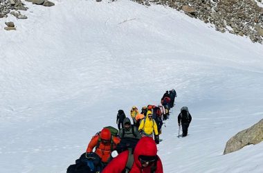 Group of trekkers hiking through snowy terrain in Hampta Pass, India.